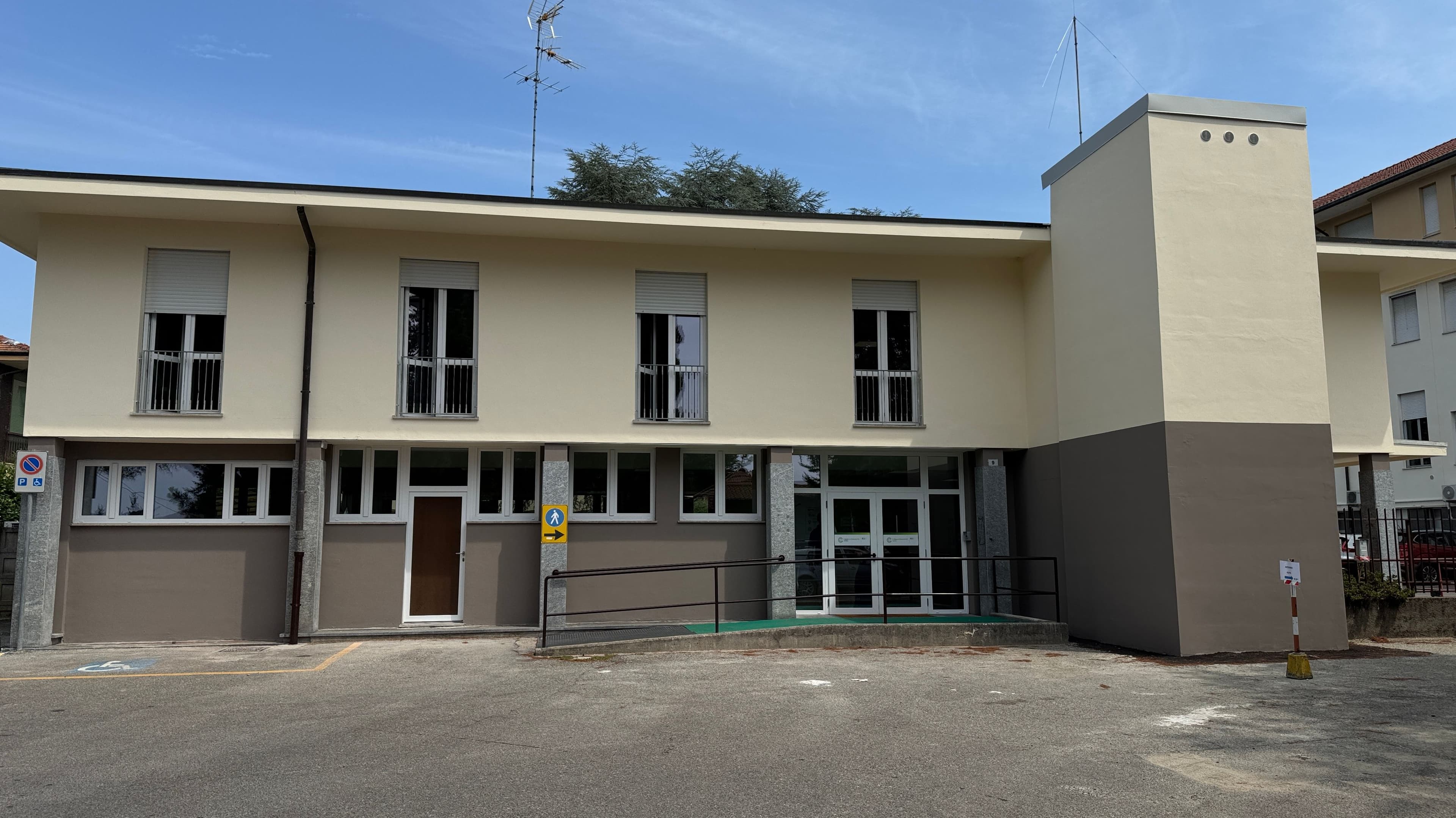 Ingresso della Casa di Comunità di Angera, edificio sanitario con accesso accessibile tramite rampa e porte vetrate.