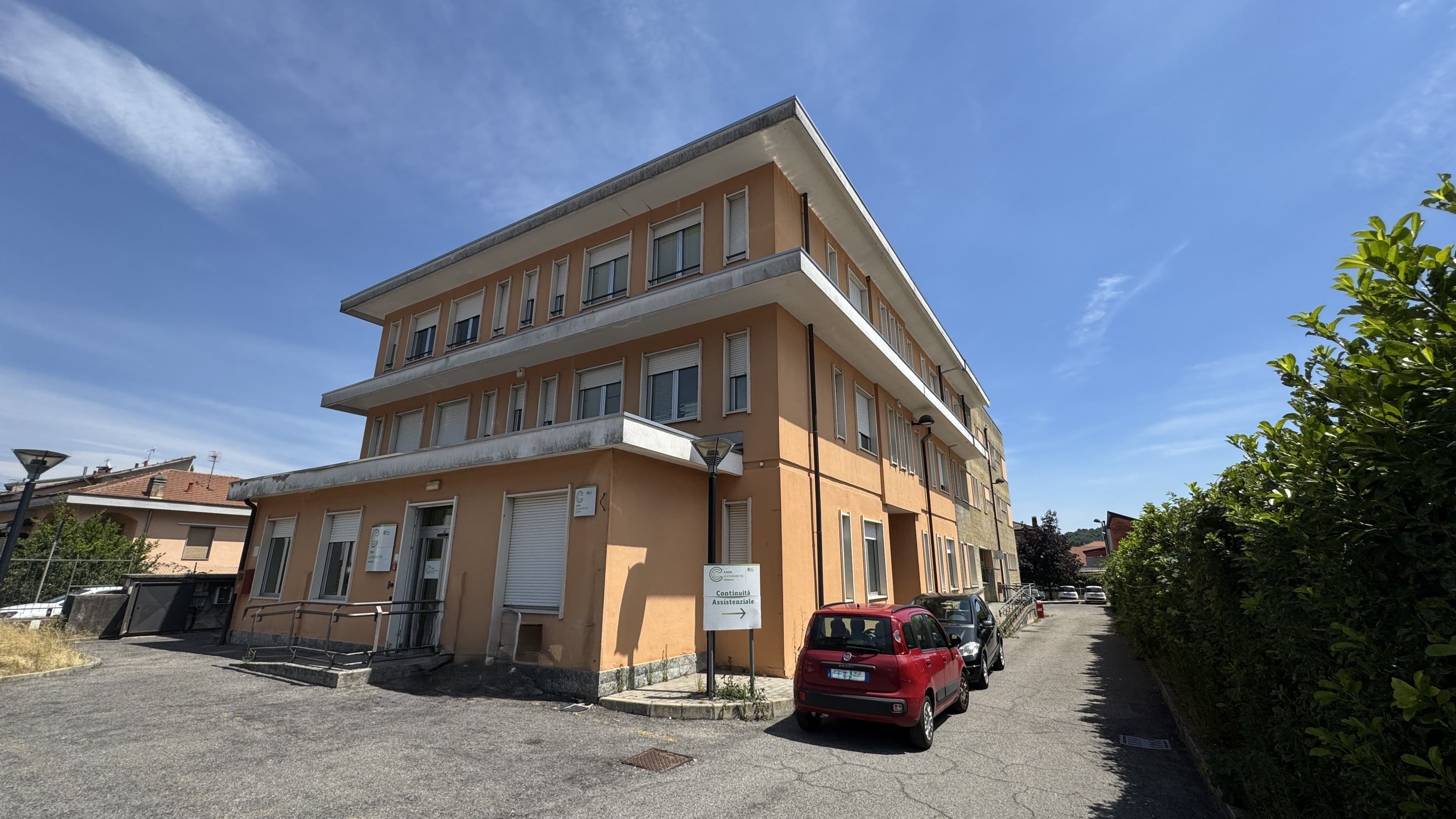 Edificio della Casa di Comunità di Arcisate con ingresso principale accessibile tramite rampa, segnaletica sanitaria e area esterna con parcheggi e percorso di accesso.