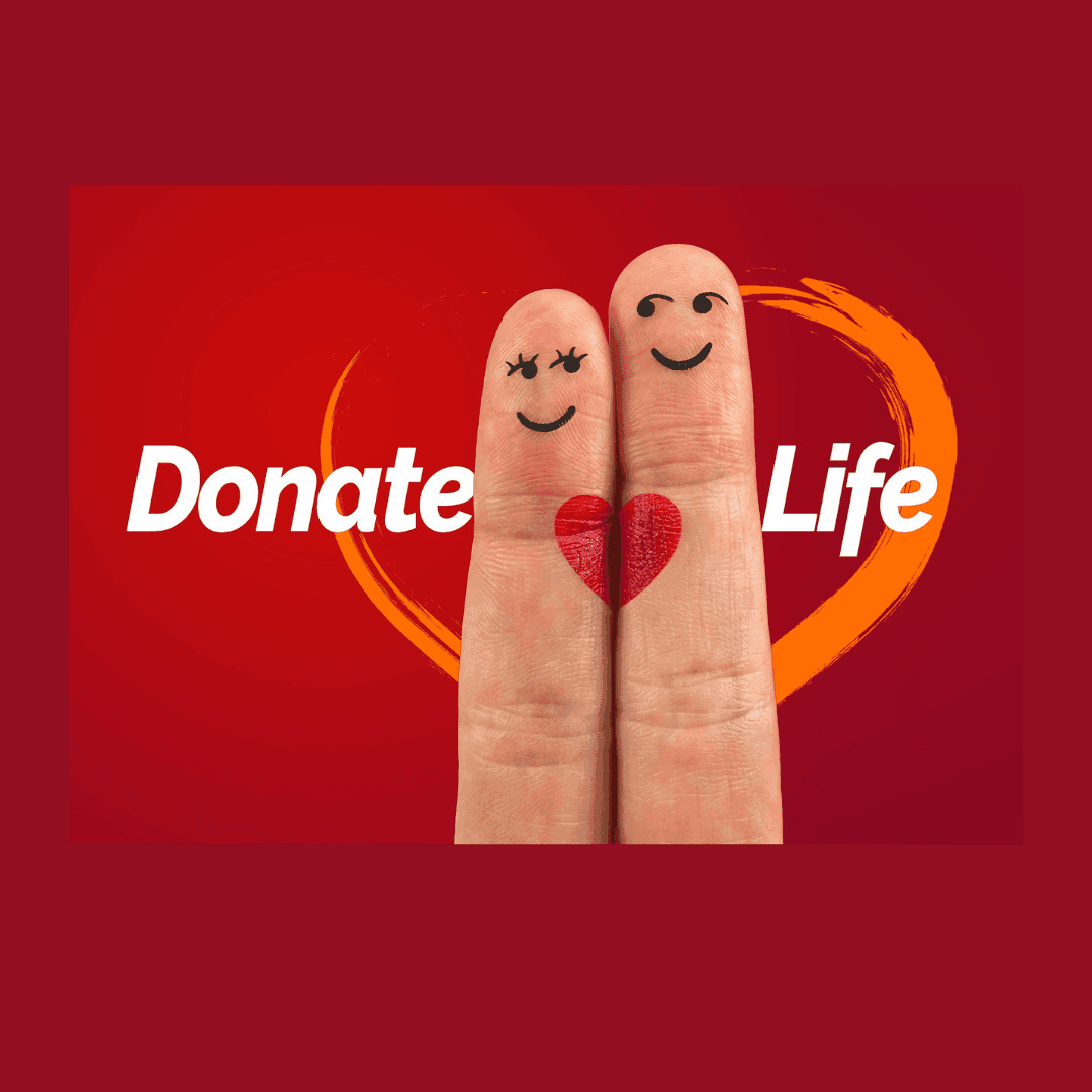 Due dita con volti sorridenti e un cuore rosso disegnato, su sfondo rosso con la scritta “Donate Life”.